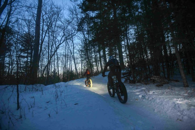 Two people fat biking at night