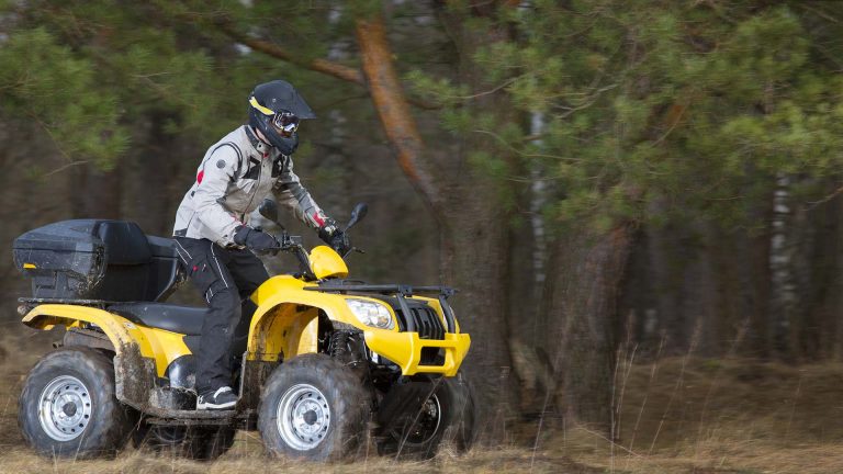 Guy riding a yellow ATV on a dirt trail