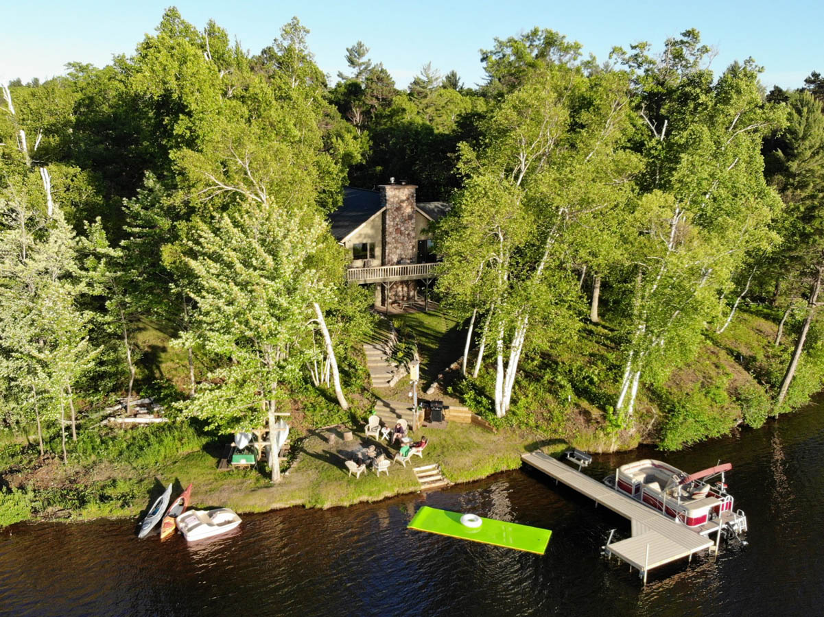 Drone shot of cabin and dock on the water nested in the woods