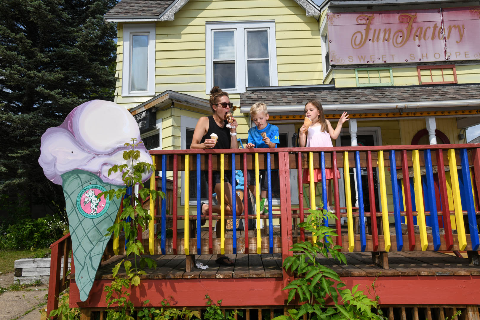 A family eating sweet ice cream treats in front of the Fun Factory Sweet Shoppe