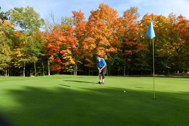 A man going for a long put at Big Stone Golf Course in the fall