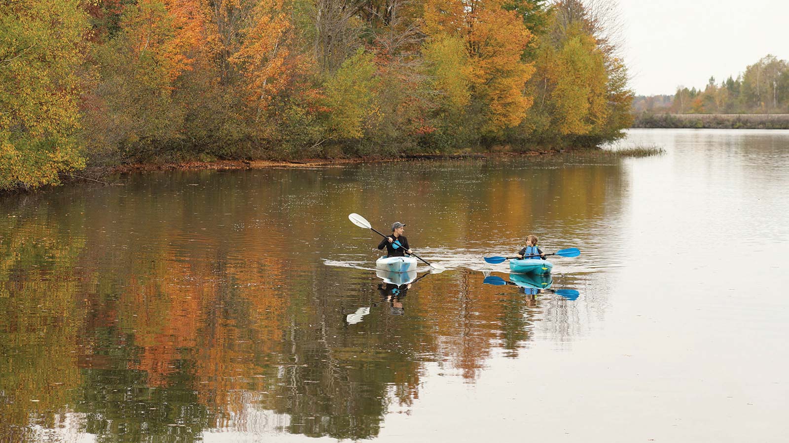 Two people kayaking the waters in autumn