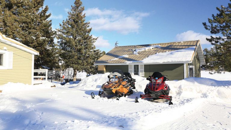 Related Article: Your snowmobile trip planner | Two snowmobiles parked outside of a resort surrounded by snow