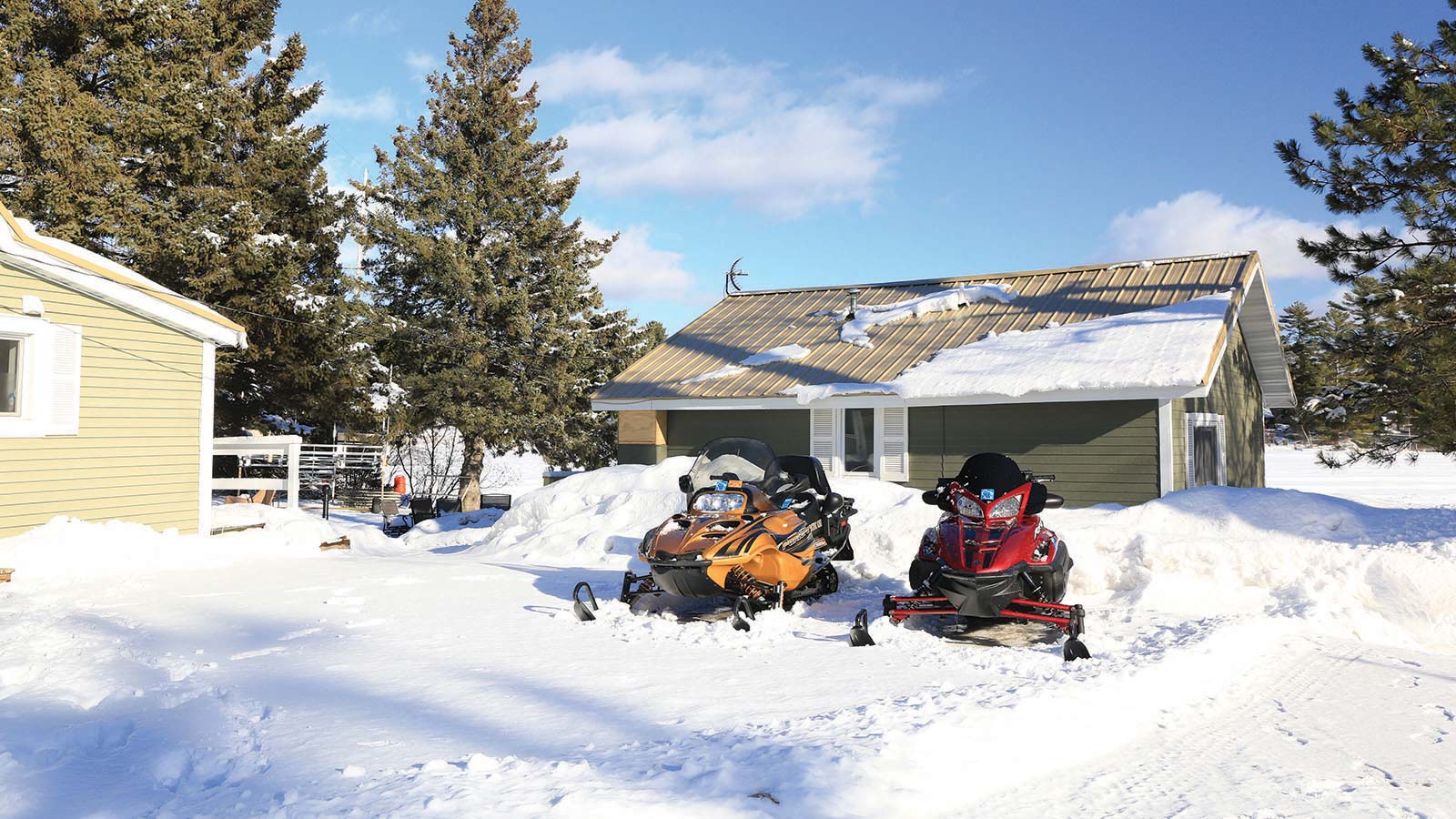 Two snowmobiles parked outside of a resort surrounded by snow