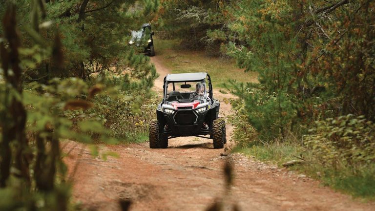 UTV driving on a dirt trail surrounded by trees
