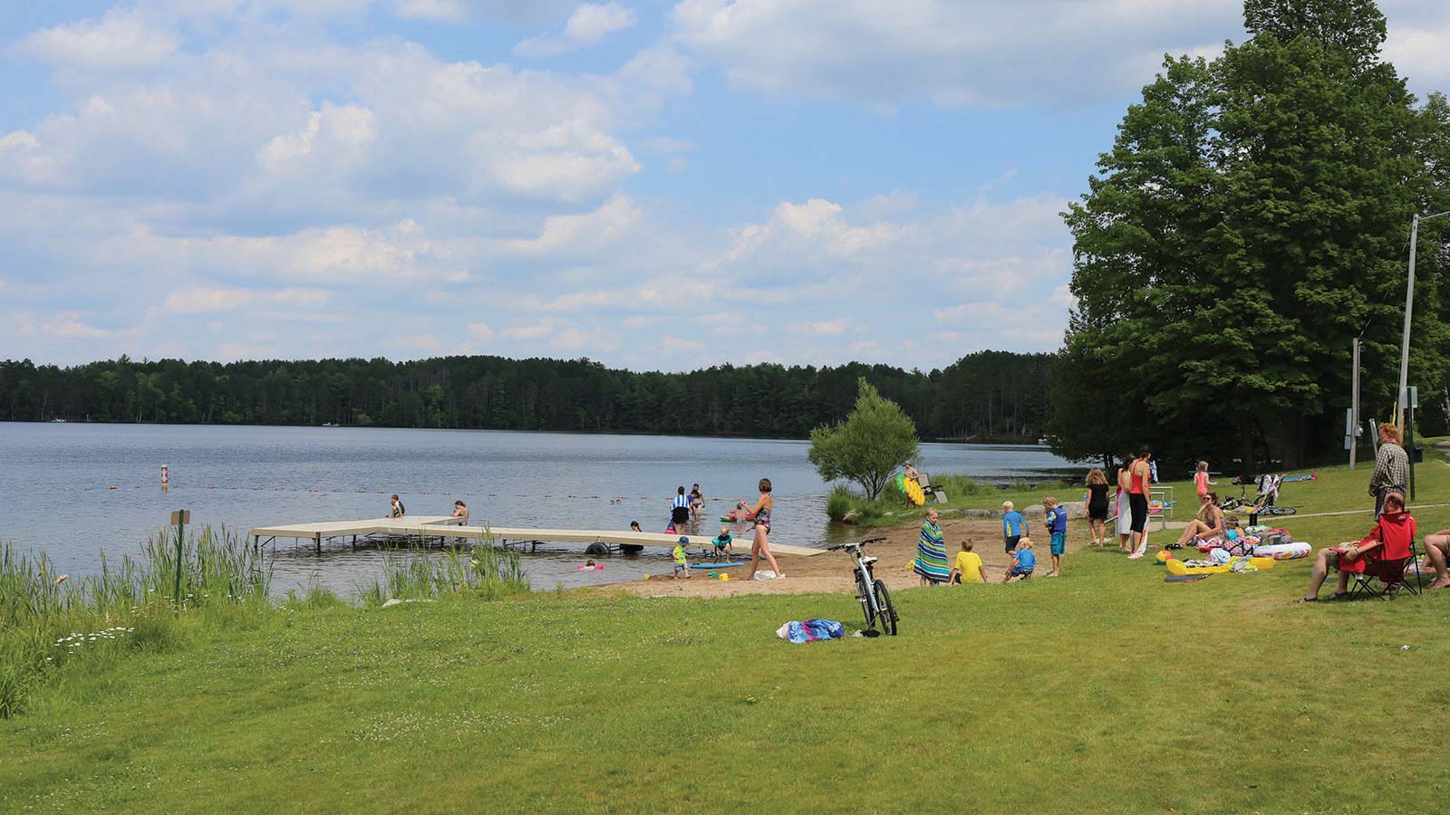 People enjoying the beach with a dock on a summer day