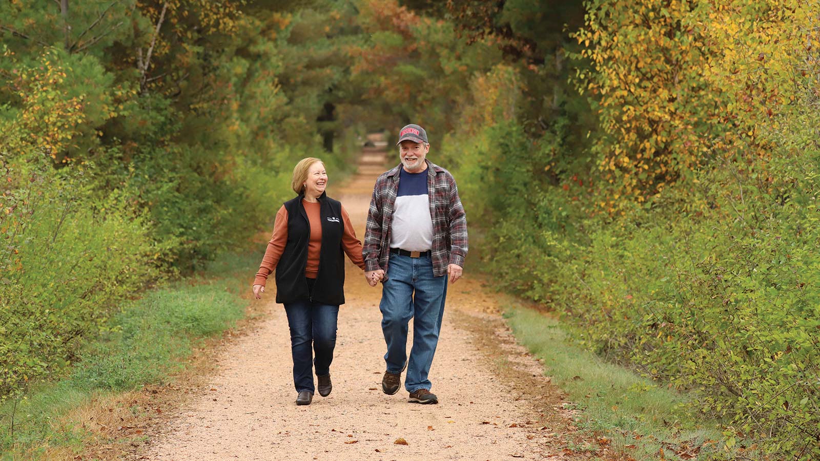 Couple walking on the trail holding hands in the fall
