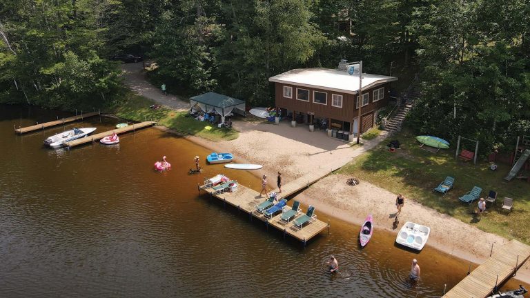 Drone bird's eye view shot of a resort with a dock on the water. People are partaking in water based activities
