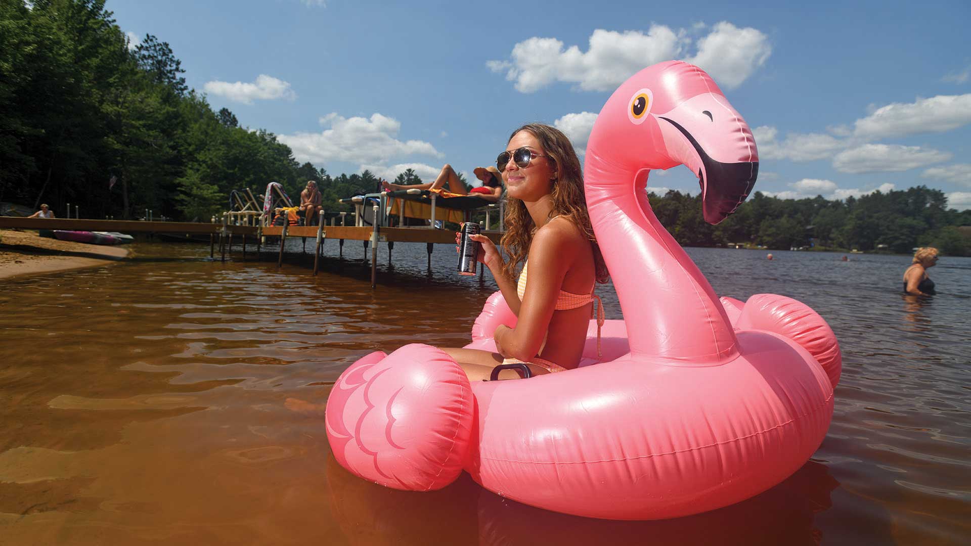 Girl sitting in flamingo tube floating on the water in front of Brekke's Fireside Resort