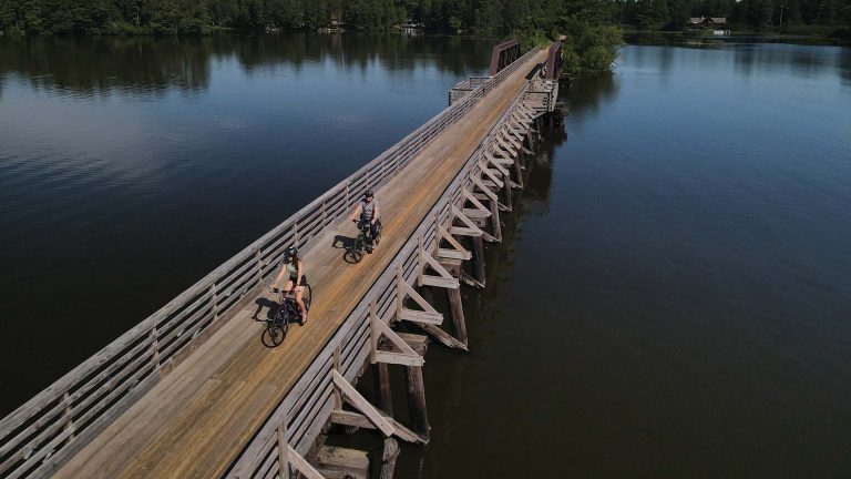 Friends biking over the Trestle Bridge surrounded by water