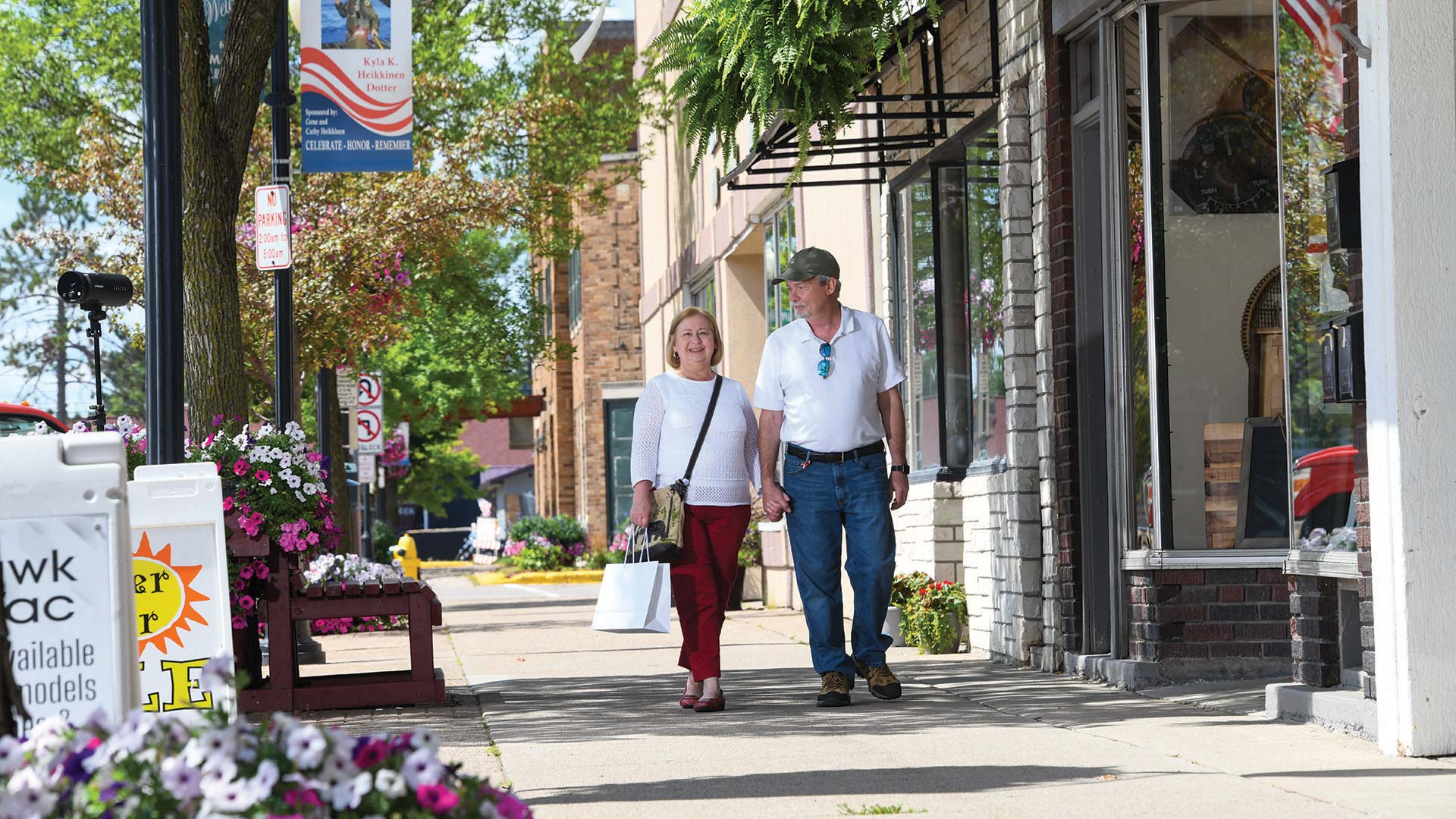 Couple walking the sidewalk next to some shops in downtown Tomahawk
