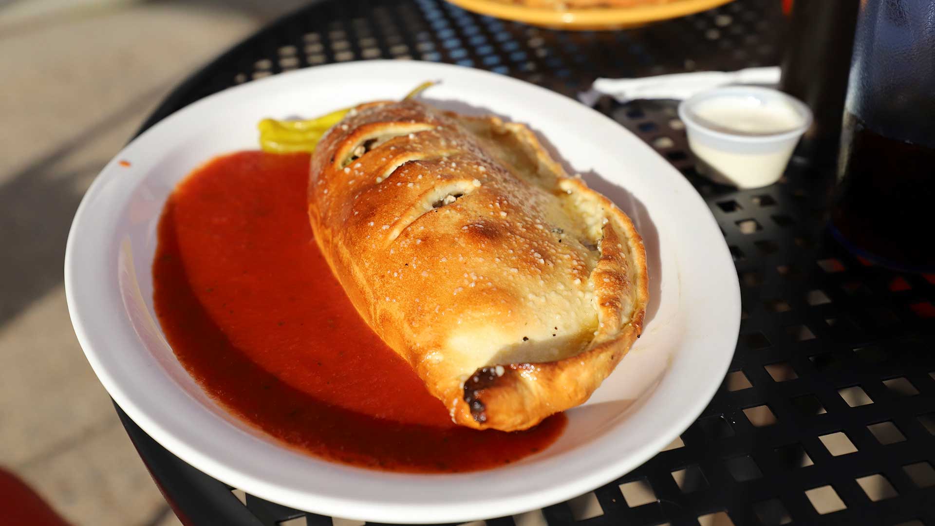 Visit Oneida County This Summer | Calzone on the outdoor dining area at Bambinos Pizza
