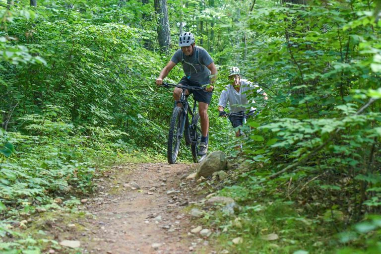 Two men mountain biking in the woods at Washburn Lake Trail