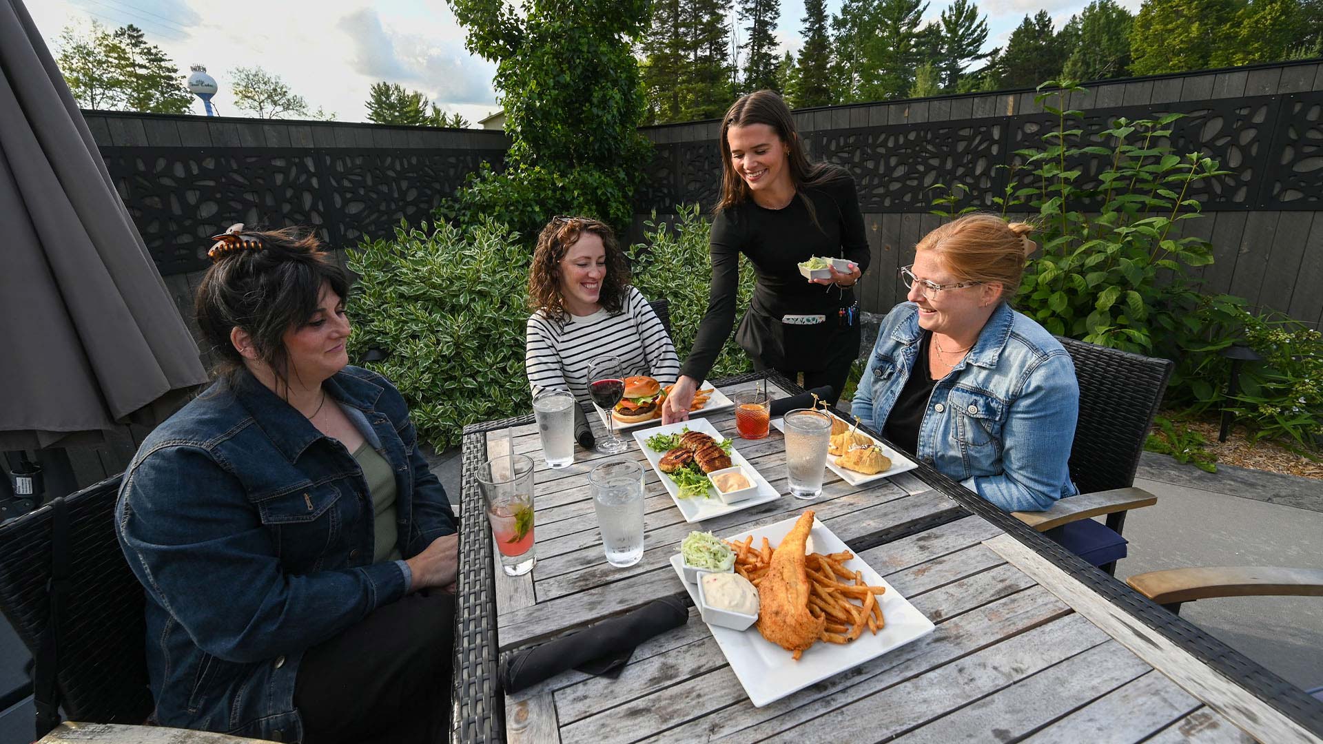 EXPLORE ONEIDA COUNTY THIS SPRING | Food being served to a group of friends sitting outside at Claytons 1881 Room