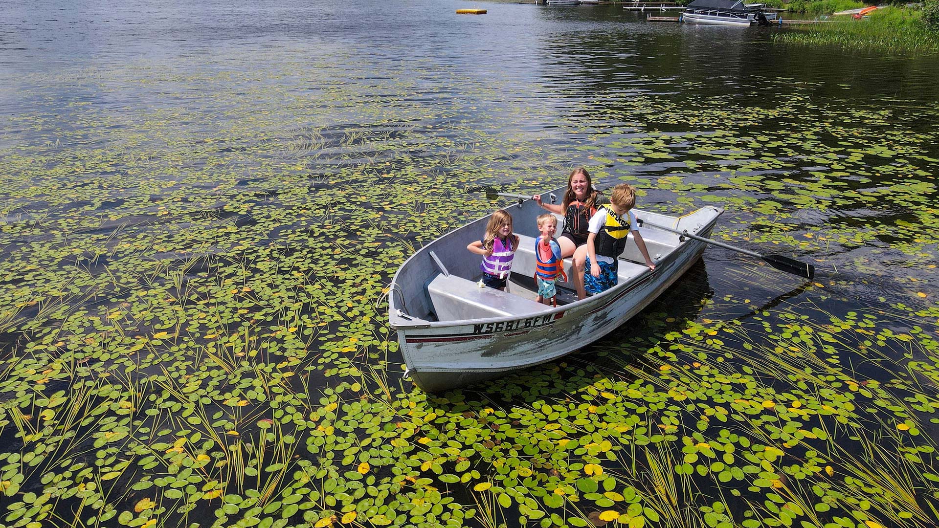 Canoeing, Kayaking & Paddleboarding | Mom and kids in a canoe surrounded by lilly pads