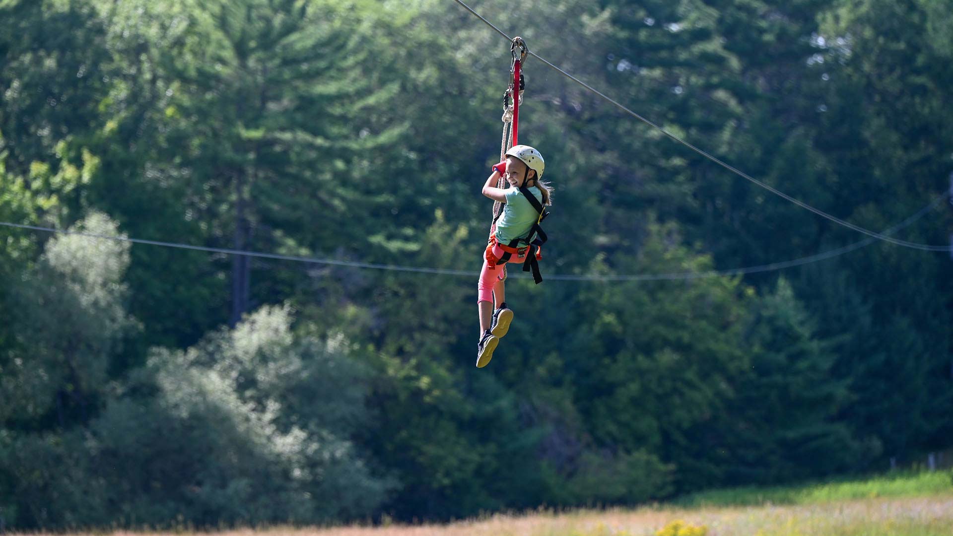 Attractions | Girl sliding down the zipline at Northwoods Zipline Adventure