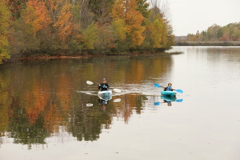 Canoeing, Kayaking & Paddleboarding | A mother and son kayak the Wisconsin River with fall trees behind them