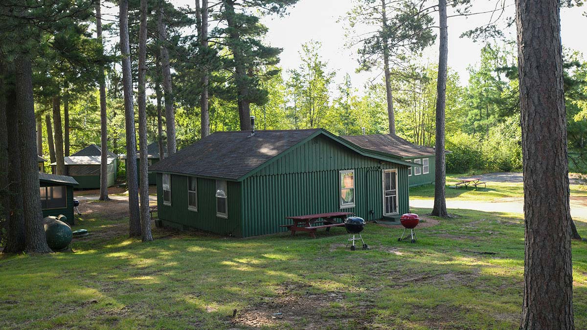 Plan Your Summer Vacation to Oneida County | exterior of a green cabin in the woods at Karch's