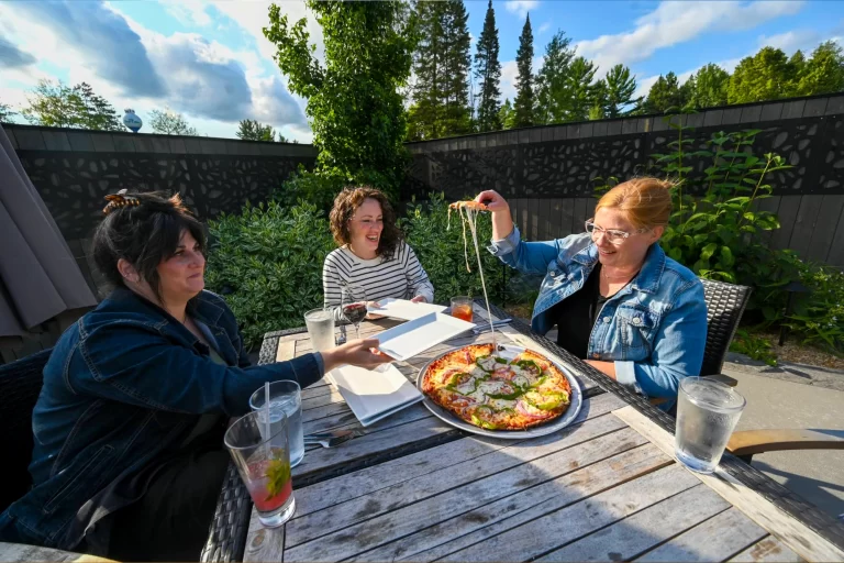 Related Article: Outdoor dining in Oneida County | Three women sitting at a table eating pizza at Clayton’s 1881 Room in Three Lakes, WI